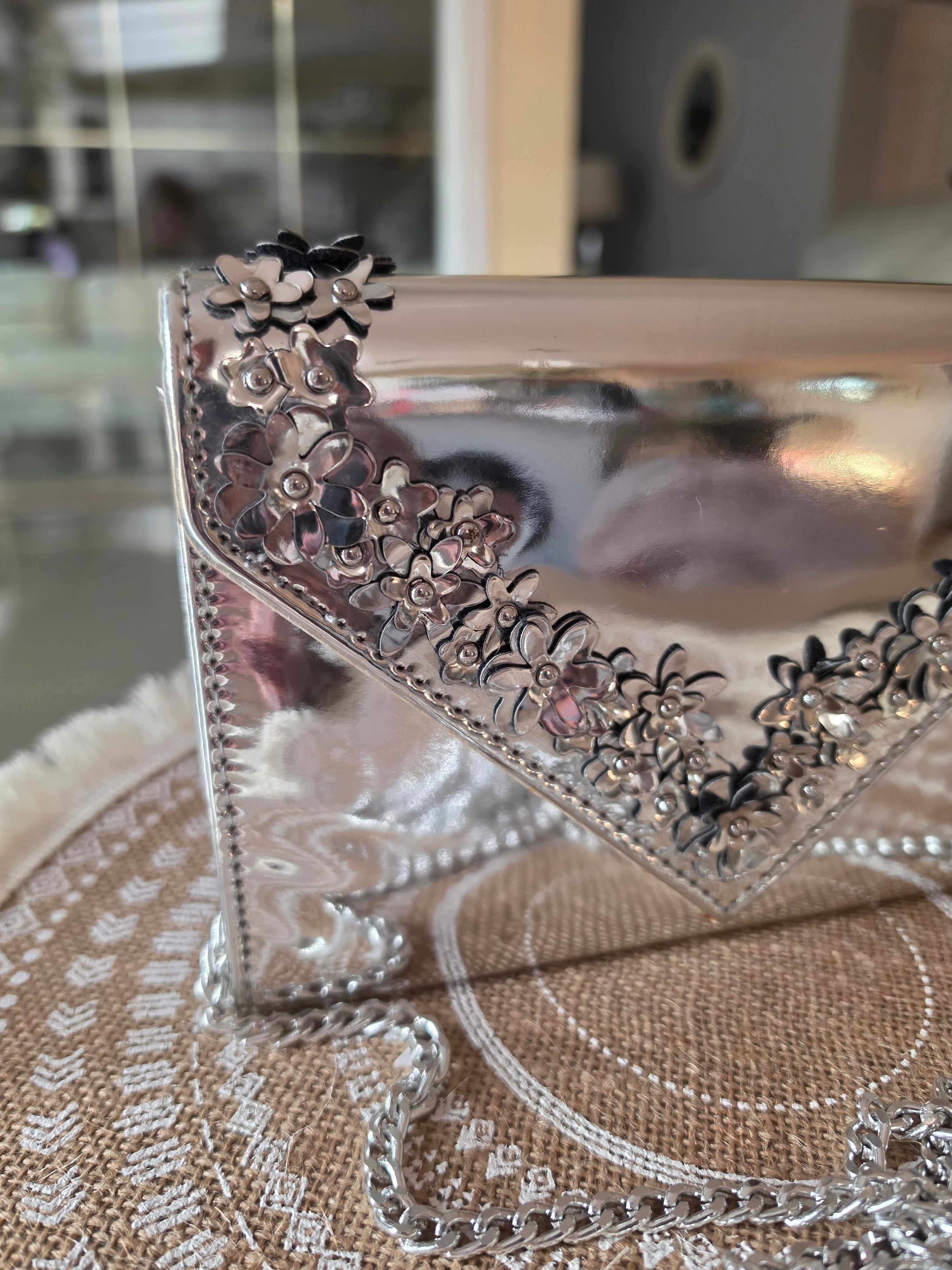 ALDO silver metallic clutch — close-up floral embellishment
