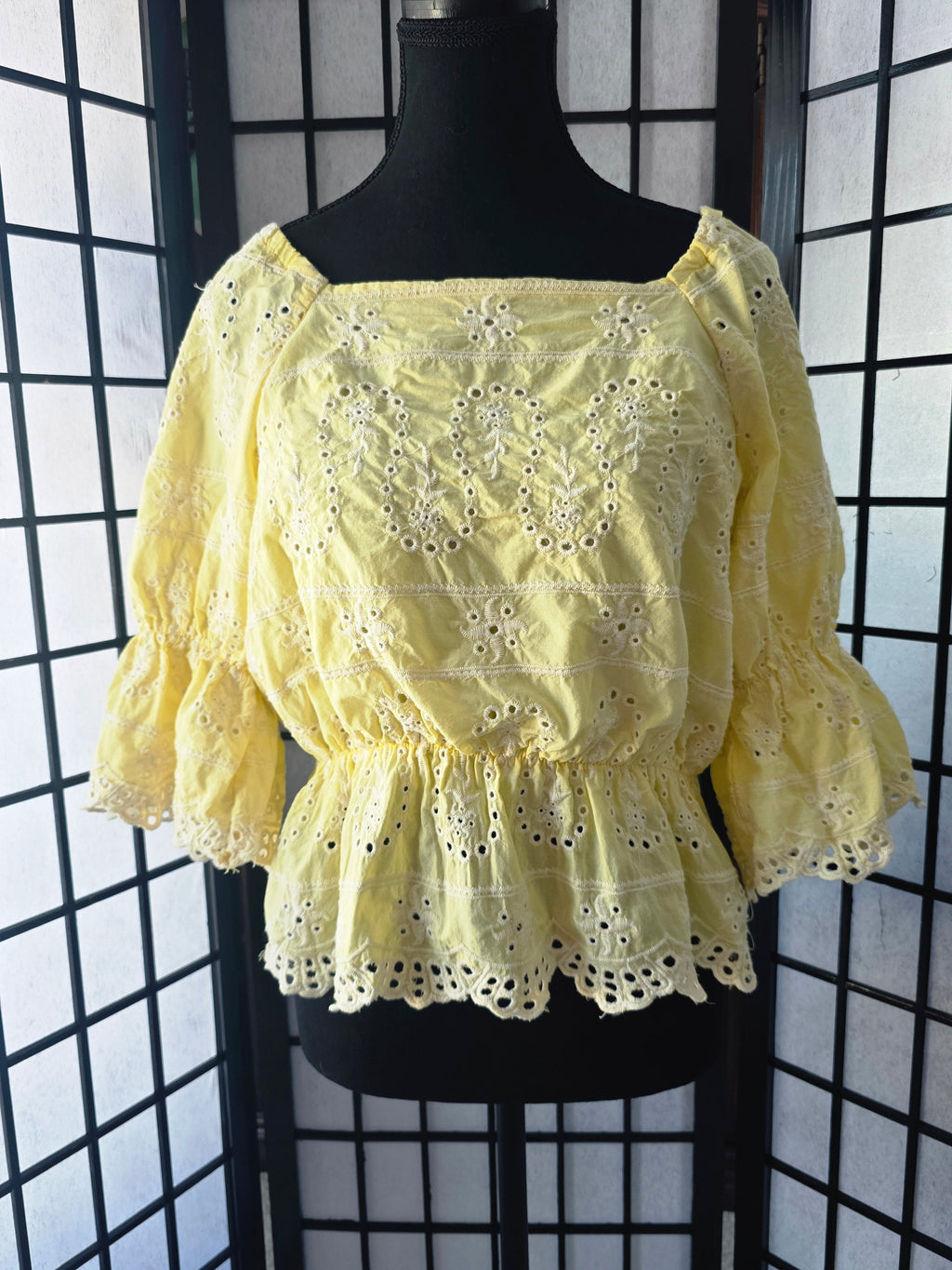 Yellow lace top on a mannequin against a black grid background