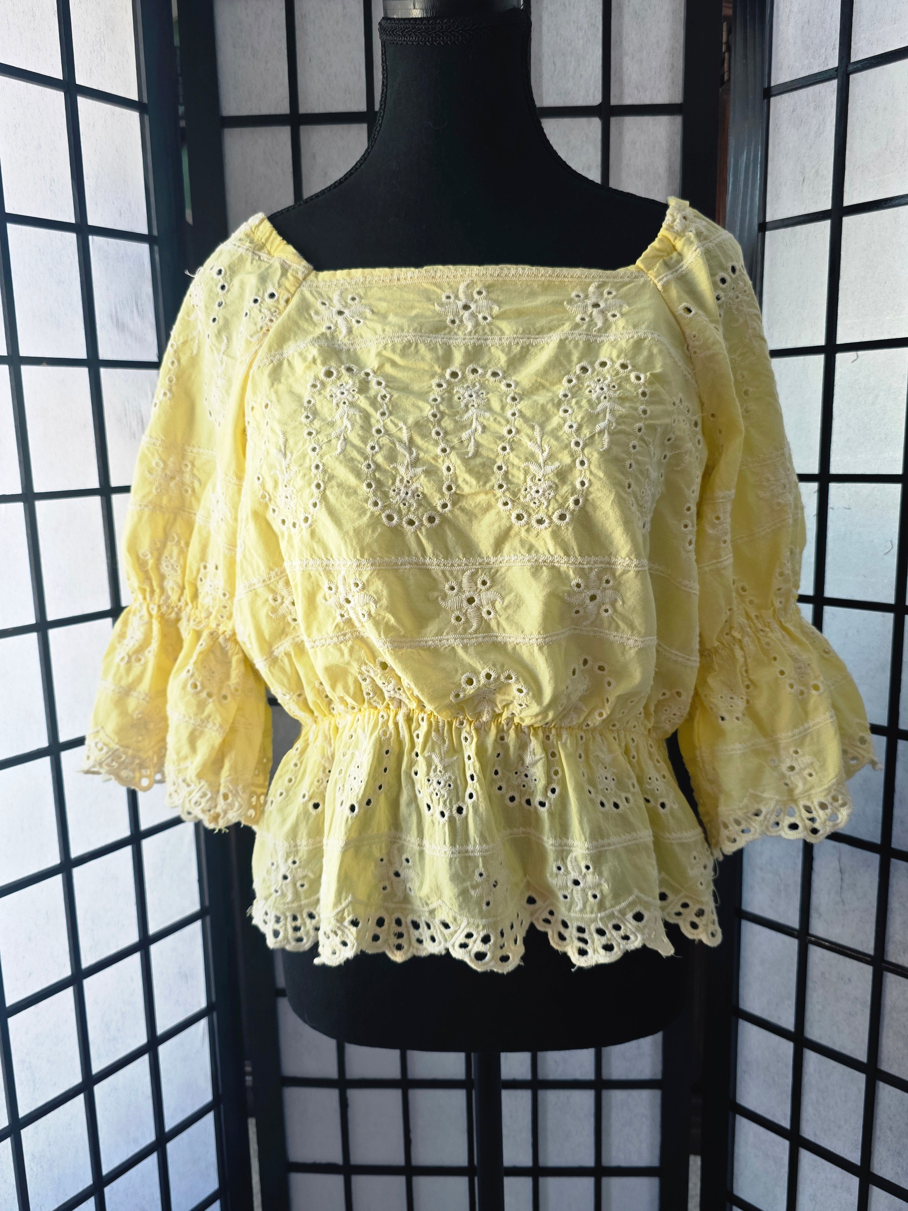 Yellow lace top on a mannequin against a black grid background