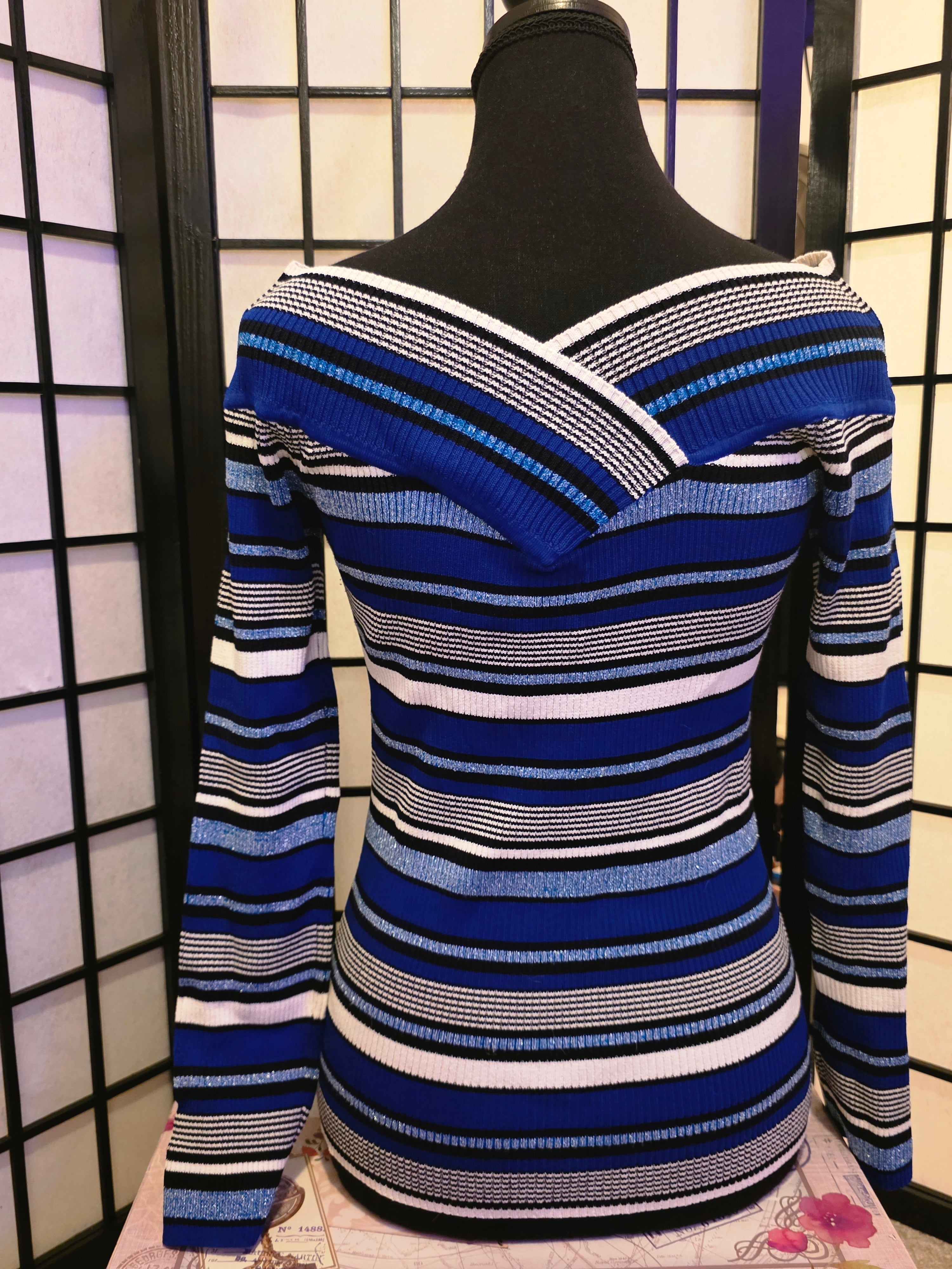 Blue and white striped sweater on a mannequin against a black and white checkered background